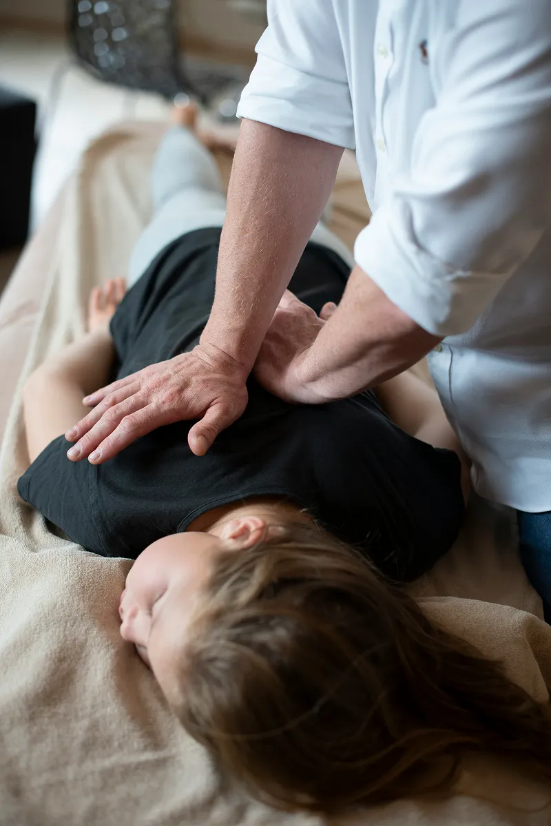 Person laying on a stretcher while receiving a maneuver on the spine from a chiropractor