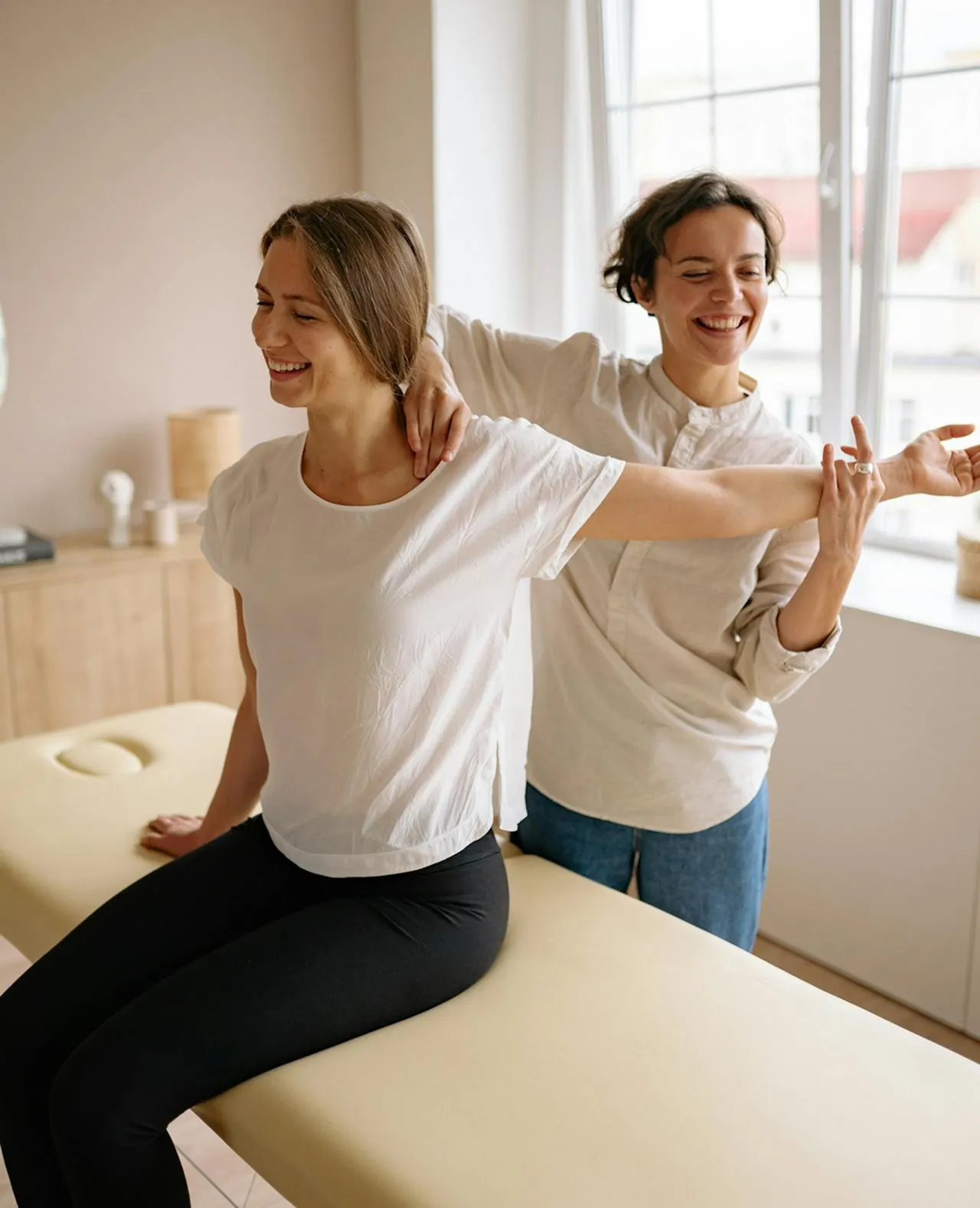 Chiropractor woman doing a maneuver over the shoulder of a woman over a stretcher